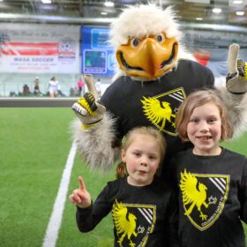 Eagles mascot with two fans holding one finger up
