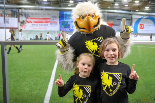 Eagles mascot with two fans holding one finger up