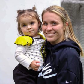 Blonde woman holding child after soccer game